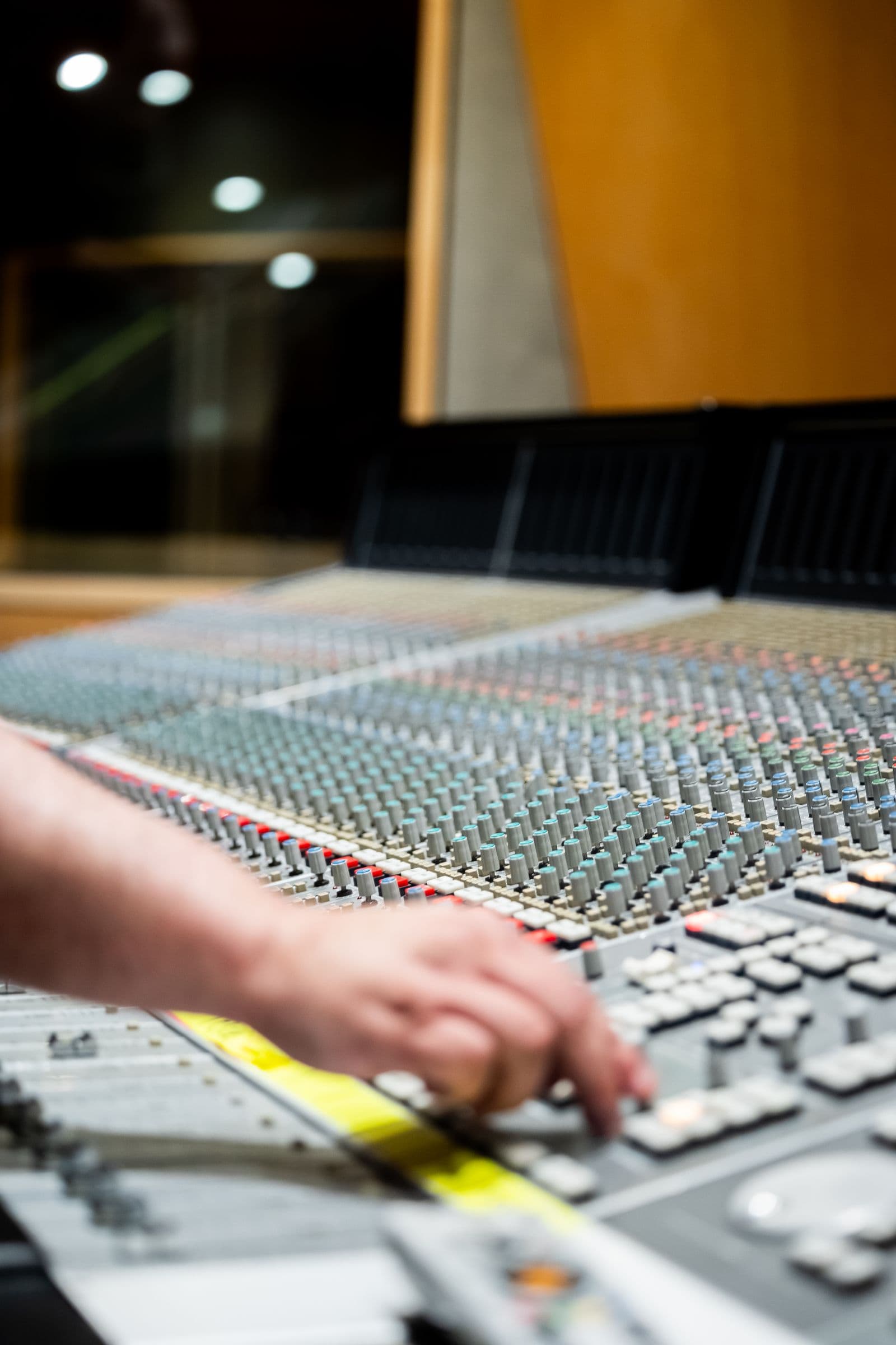 A producer's hand working a studio mixing console